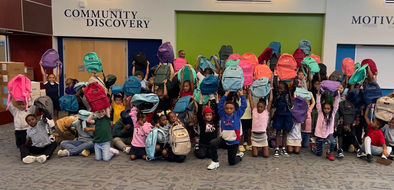 Students celebrating with backpacks at a CCL-KIDS drive