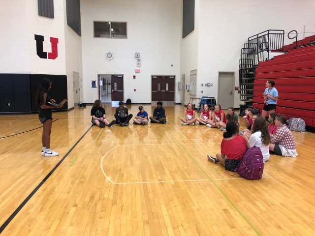 Kriti Gupta leading a youth leadership workshop with students seated in a circle in the gymnasium
